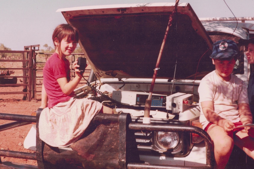 Aticia as a kid with her brother, perched on a truck and holding up its radio.