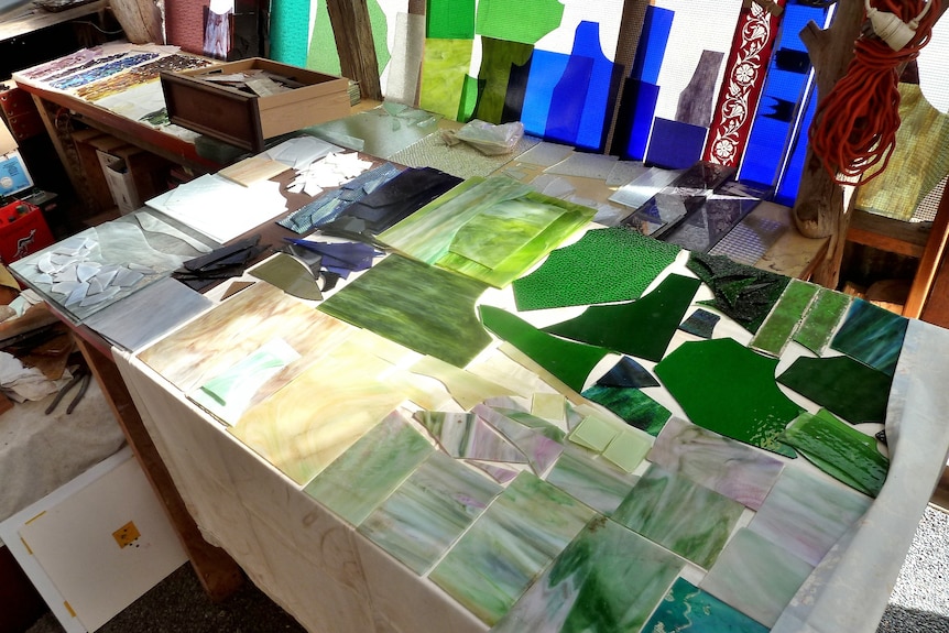 Table of coloured glass, green and blues, lying