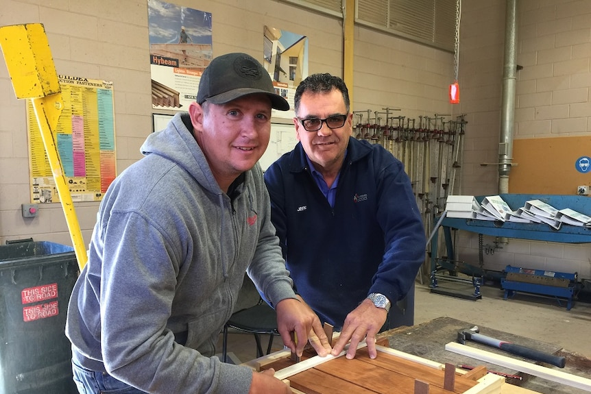 Teacher, right, shows a young man with an acquired brain injury how to do woodwork.