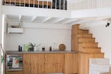 A mezzanine and small staircase create a second floor bedroom.