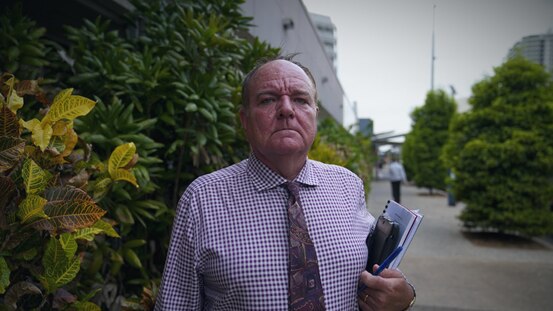 A man stands defiant with documents in hand.