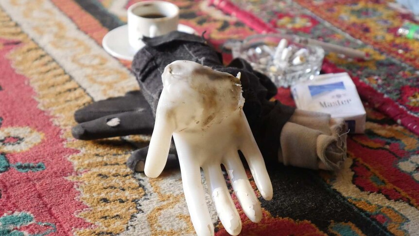 A fake plastic hand rests on a glove and an ashtray