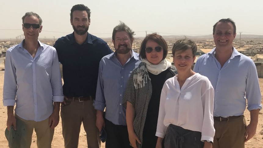 Six politicians stand together somewhere in the middle east