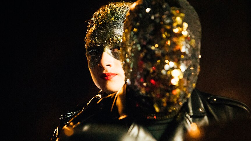 Close-up colour still of Raffey Cassidy wearing gold mask in 2018 film Vox Lux.