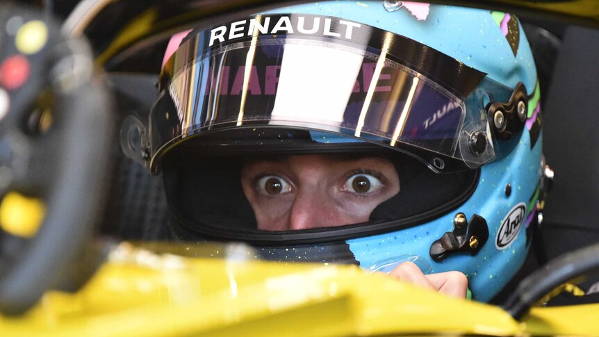 Daniel Ricciardo's wide and surprised eyes are visible through the visor of his helmet as he sits in his car.