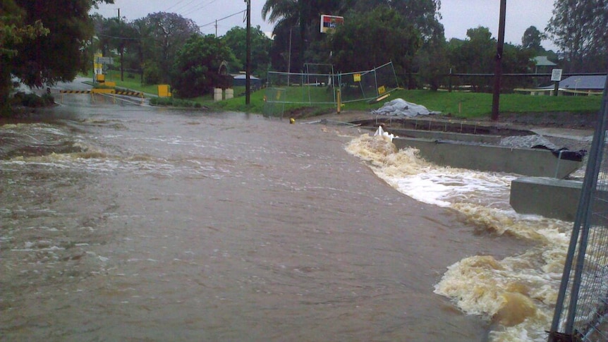 Floodwater from Ithaca Creek gushes across Bowman Parade in the Brisbane suburb of Bardon.