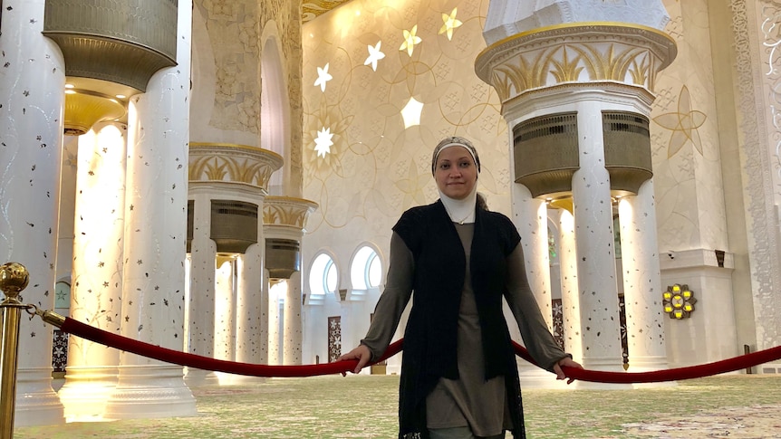 A woman stands in a mosque looking at the camera.