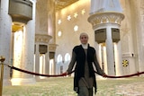 A woman stands in a mosque looking at the camera.