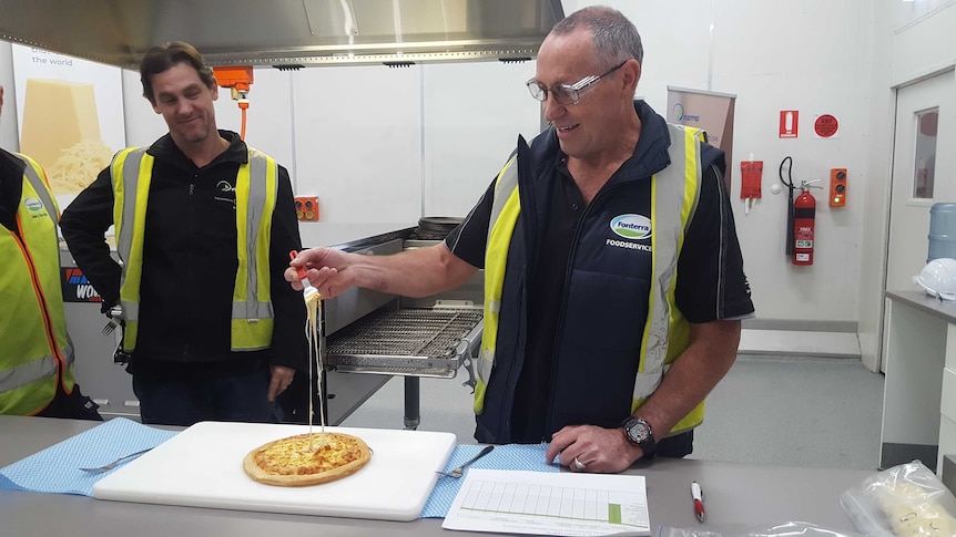 Stanhope-based cheese technician Paul Triste uses a fork to lift melted mozzarella from a freshly-baked pizza.