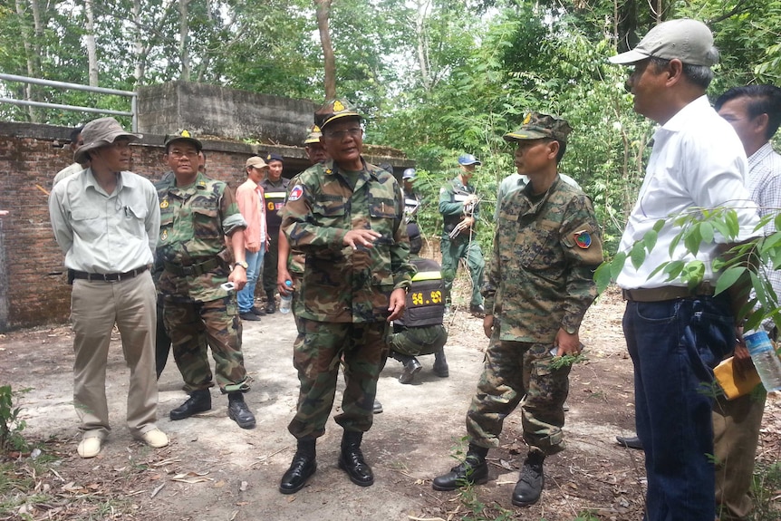 Men gather outside Pol Pot's former jungle hideaway.