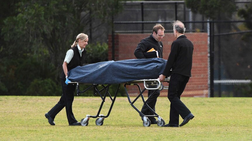 A body is removed by authorities from a crime scene at Princes Park in Melbourne.