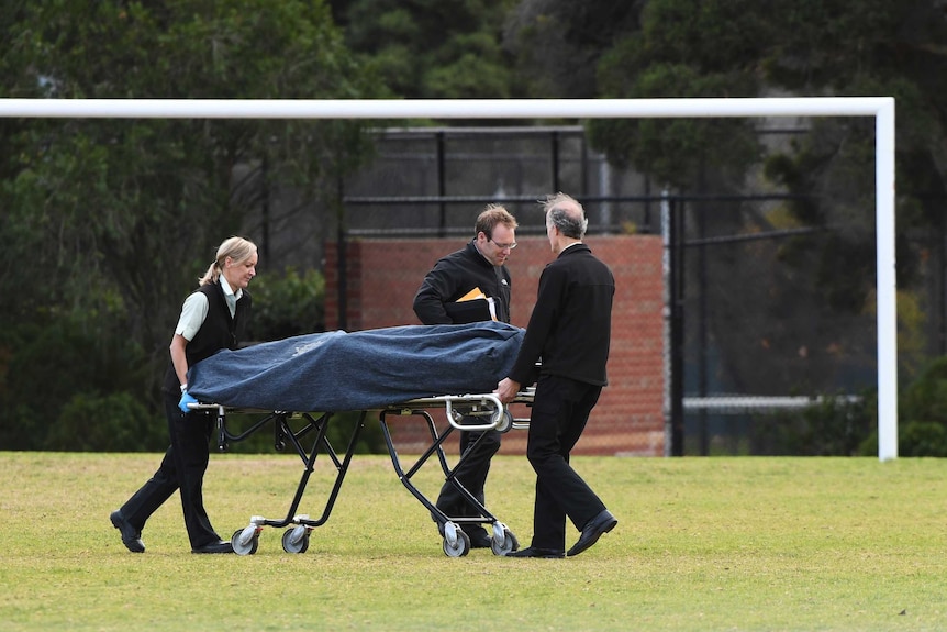 A body is removed by authorities from a crime scene at Princes Park in Melbourne.