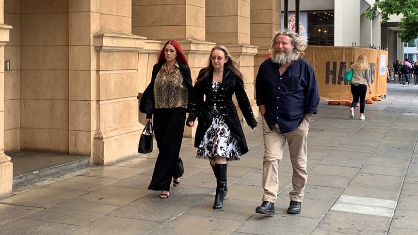 Two women and a man walking on the footpath outside a courthouse