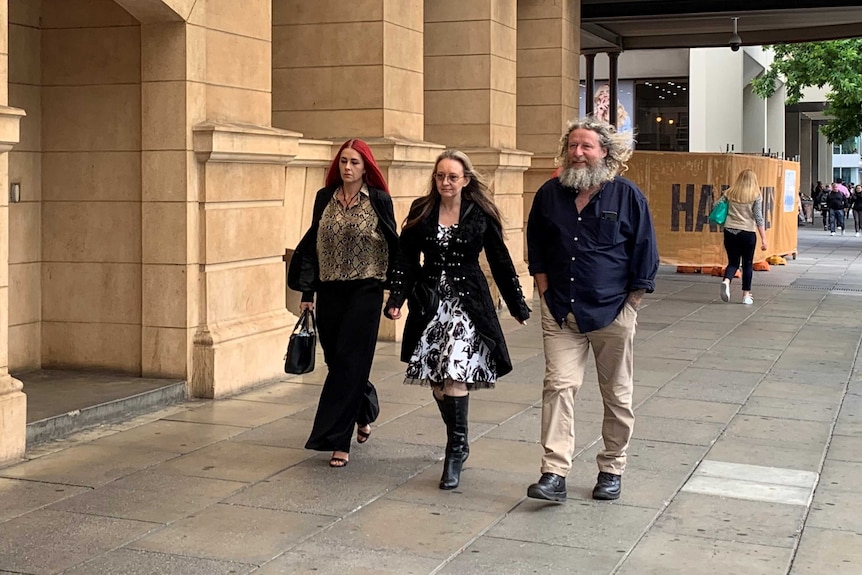 Two women and a man walking on the footpath outside a courthouse