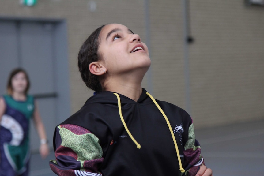 A young girl in active wear on a basketball court.