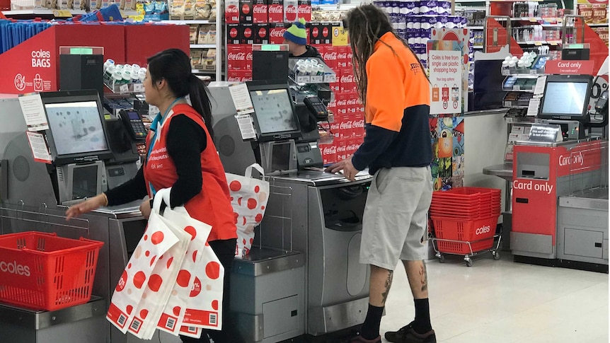 A Coles staff member holding plastic bags