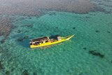 An aerial view of a yellow illegal Indonesian fishing boat in the water