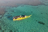 An aerial view of a yellow illegal Indonesian fishing boat in the water