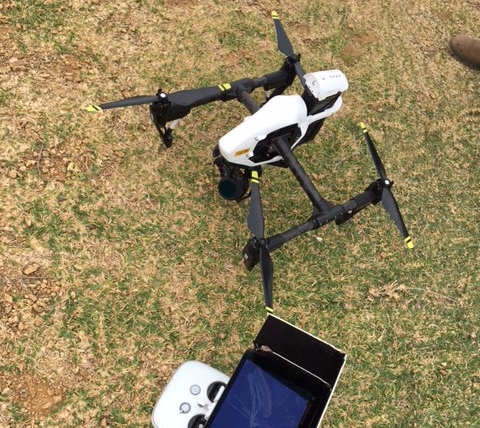 Drone and associated technology sitting on grass.