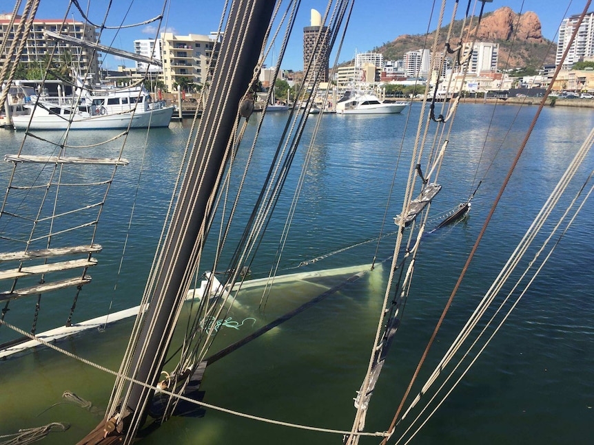 The masts of tall ship Defender showing, with the rest of the ship underwater.