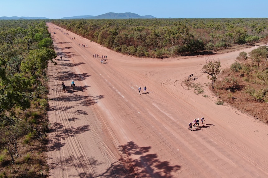 A drone shot of people walking along a dirt road