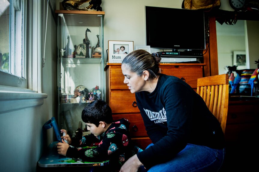 Mel Habib sits with her son Noah and he completes his school work during lockdown.
