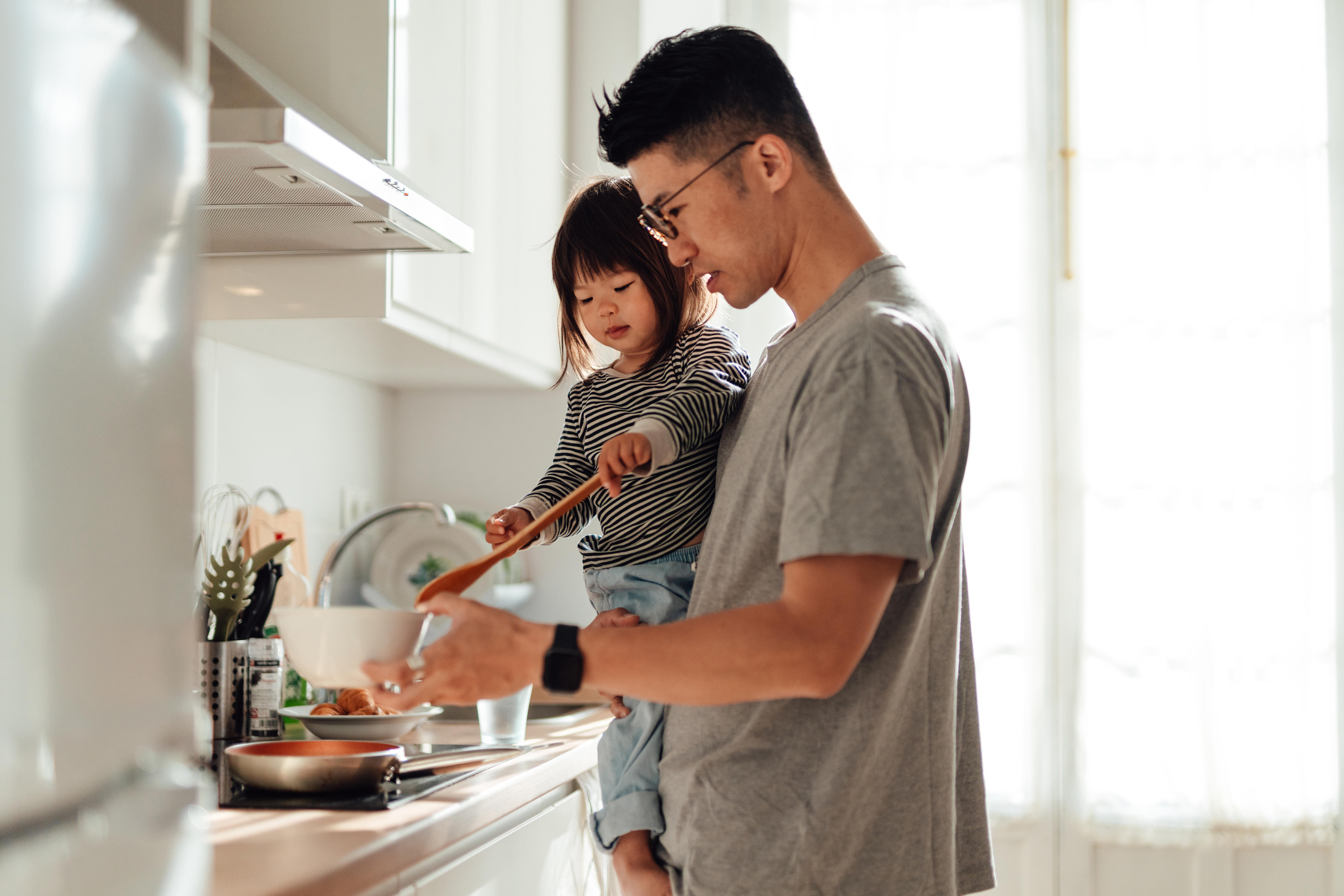 Young Asian father and daughter cooking together in kitchen at home