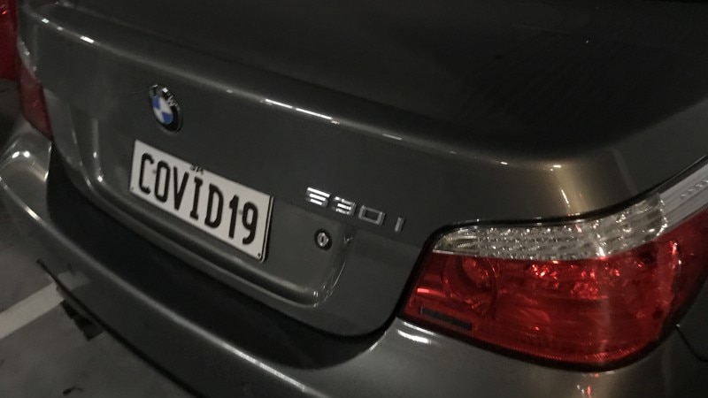 The boot of a silver bmw. The rear licence plate shows the word 'COVID19'
