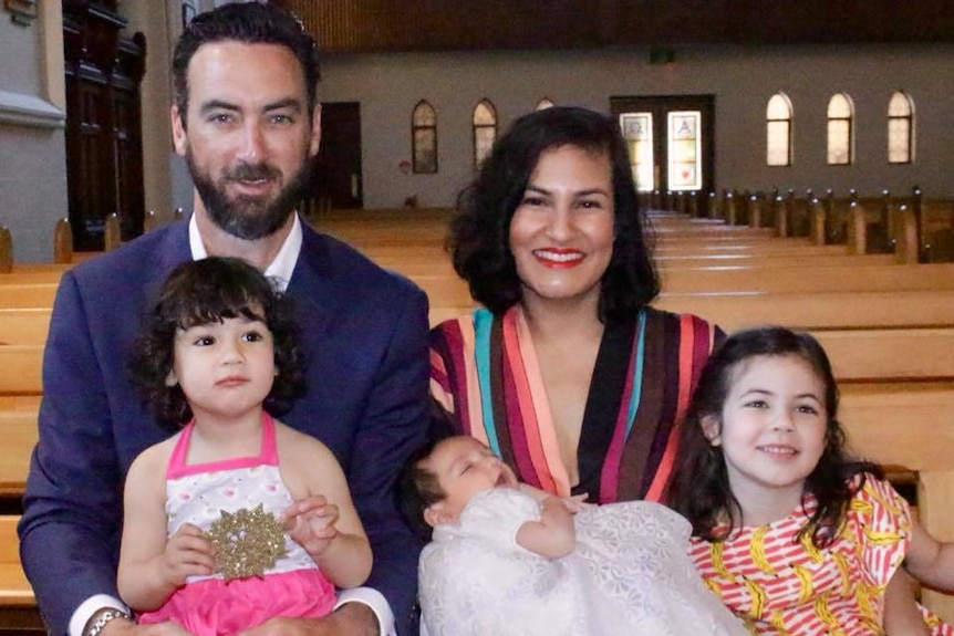 A man, woman and three children sit on a pew in a church.