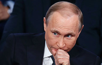 Close-up of Russian President Vladimir Putin sitting down.
