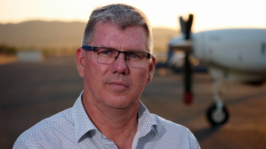 A close-up picture of a man wearing a blue shirt and glasses.