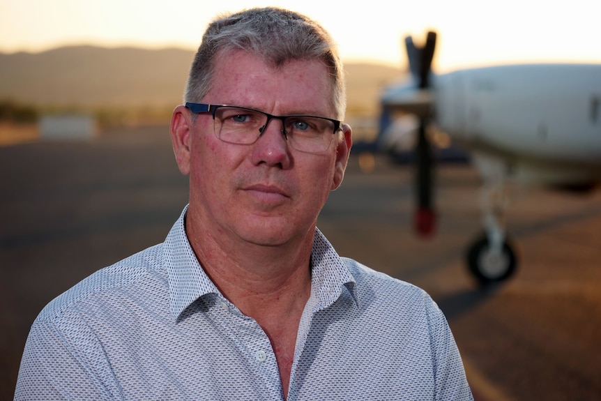 A close-up picture of a man wearing a blue shirt and glasses.