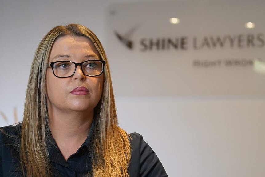 Clare Eves in front of a Shine Lawyers sign