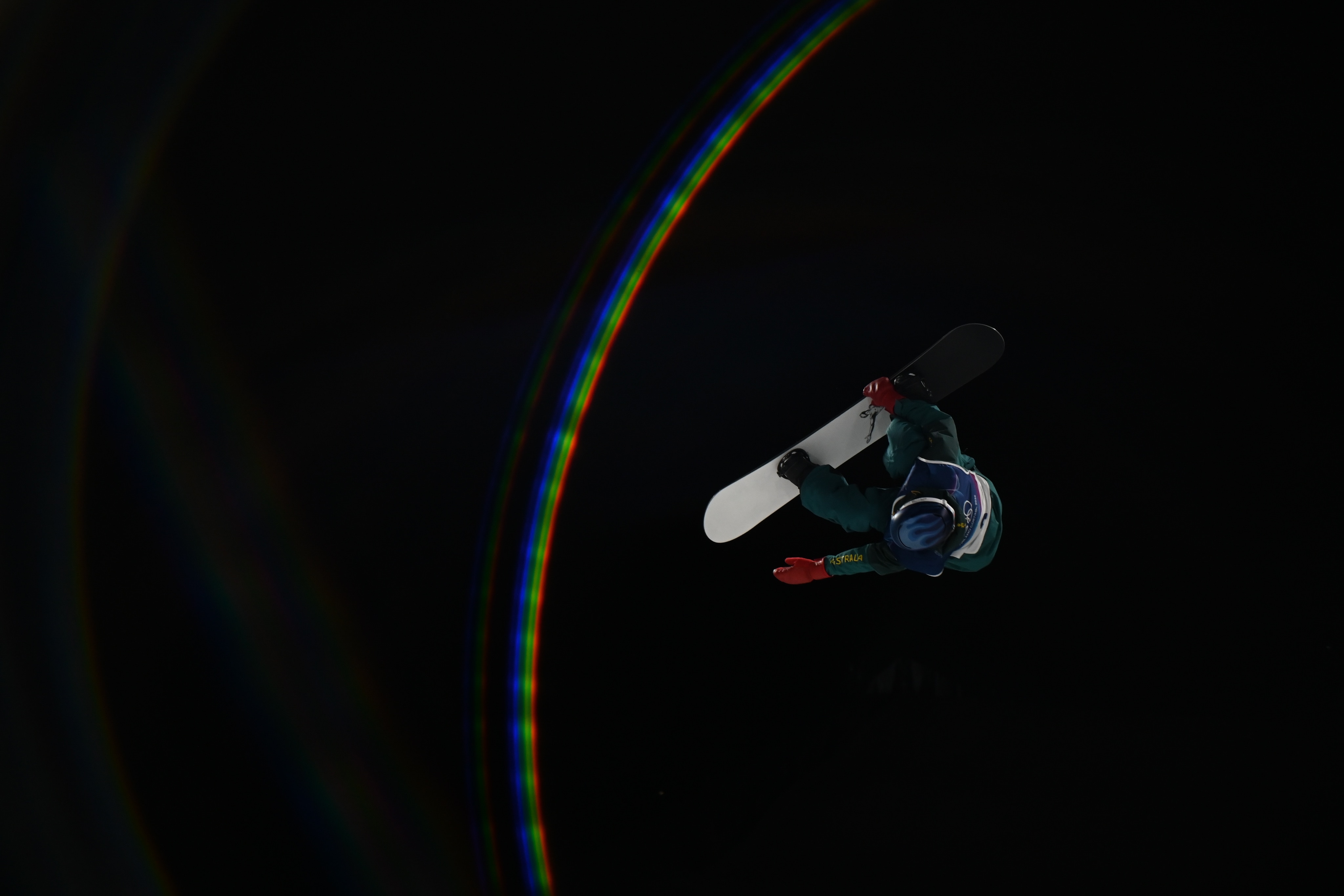 Um snowboarder voa pelo ar à noite.