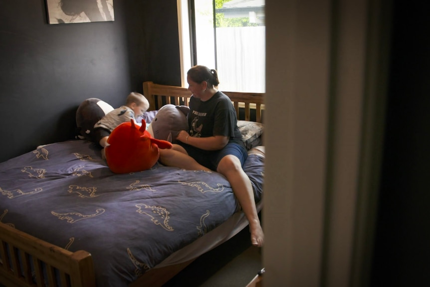 A woman sitting on a bed with her son.