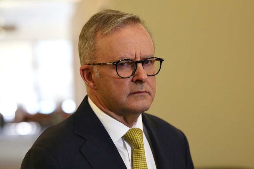 Prime Minister wearing a suit and yellow tie inside a clinical environment