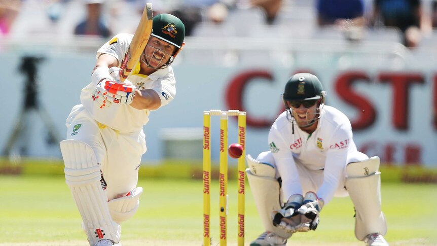 Australia's David Warner bats on day one in Cape Town as AB De Villiers looks on.