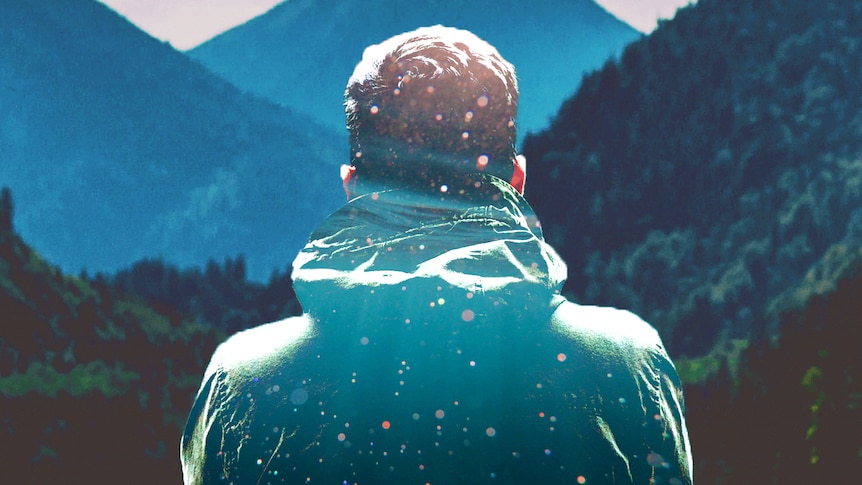 Lonely looking man looking out over mountains and pictured from behind