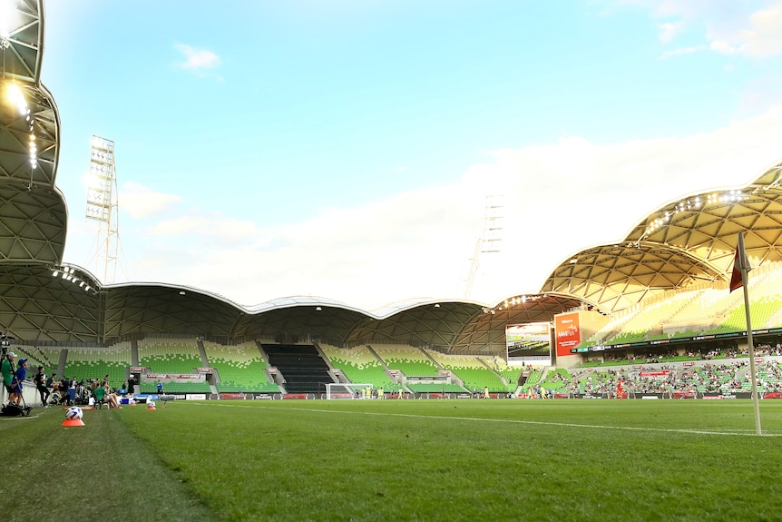 A picture looking down the length of a football pitch, with a section of the stand behind the far goal covered up. 
