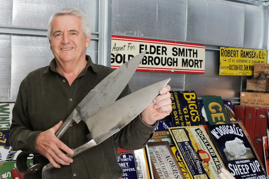 George Grant holds a pair of giant shearers in his shed