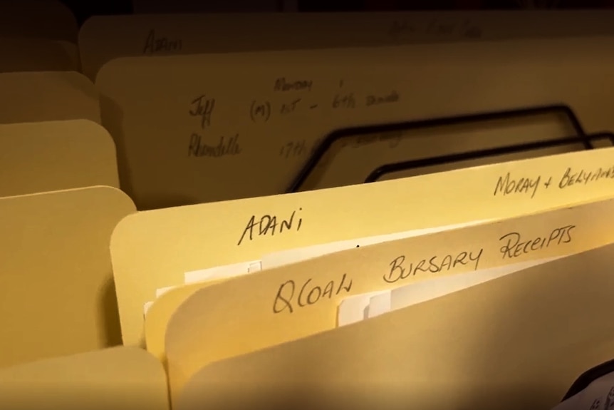 a manilla folder with "Adani" written on it, is sitting among other folders