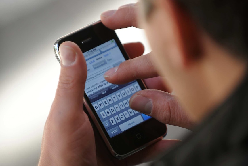 A man looks at a text message on his iPhone in Sydney, 2009.