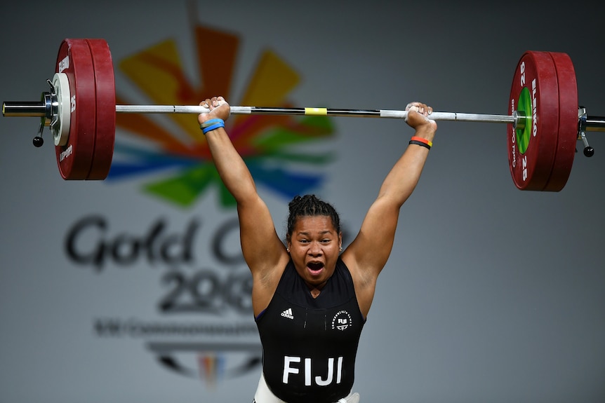A woman lifts weights above her head.
