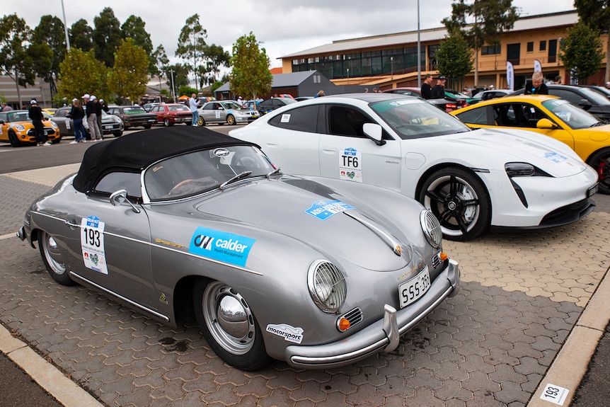 A small old fashioned Porsche sits alongside a larger modern Porsche