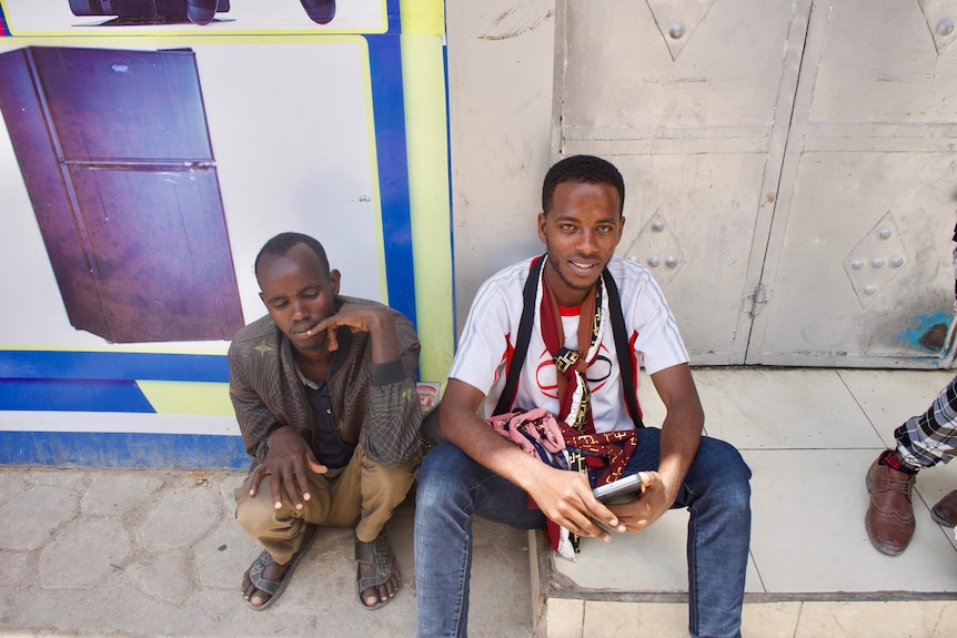 Two men sit on a step