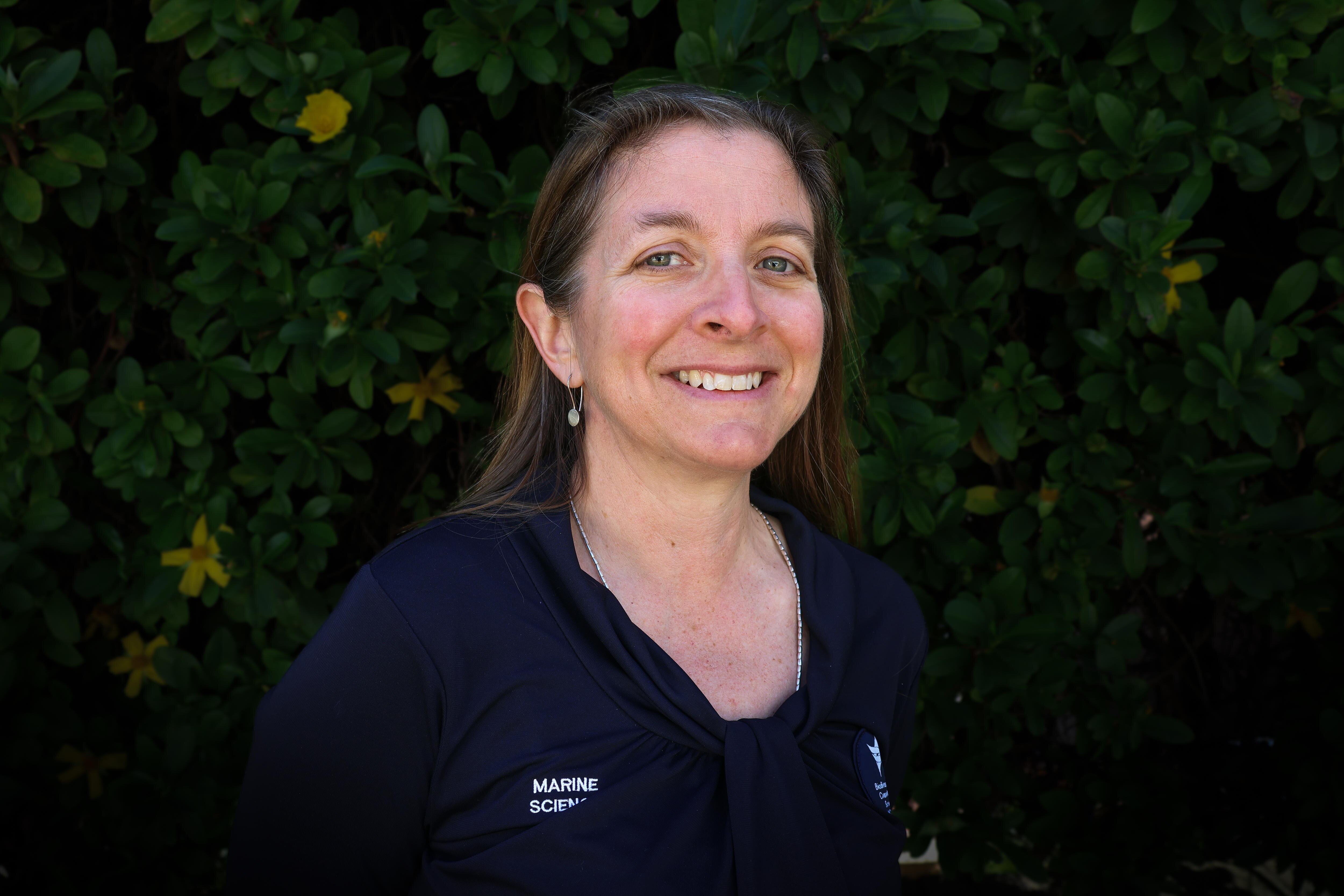 Woman with navy shirt and long dark hair smiling