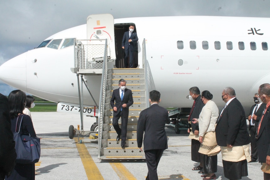 China's Foreign Minister descending stairs from plane onto tarmac