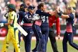 An Australian batter leaves the field as England players celebrate their win.