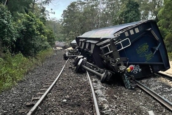 A train lies on its side on the tracks