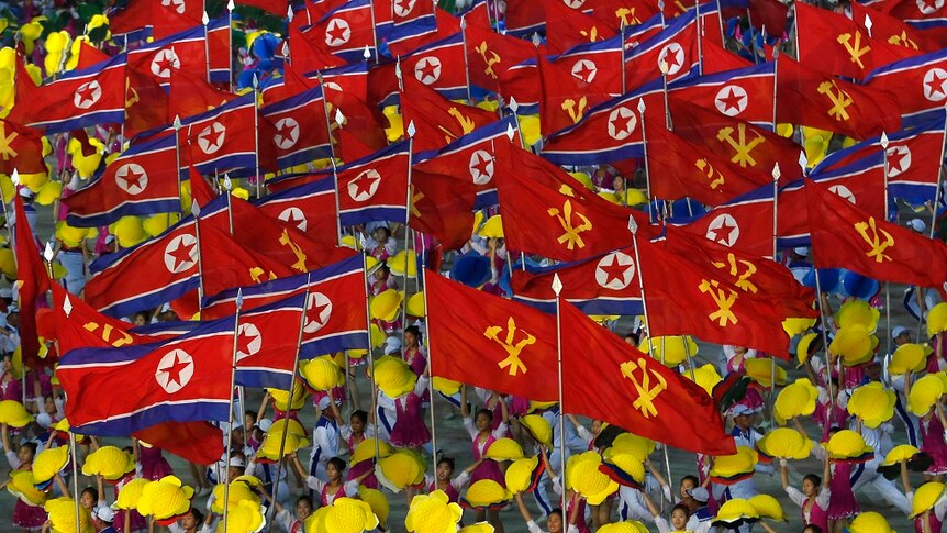 Dancers wave flags of North Korea and Korean Workers' Party